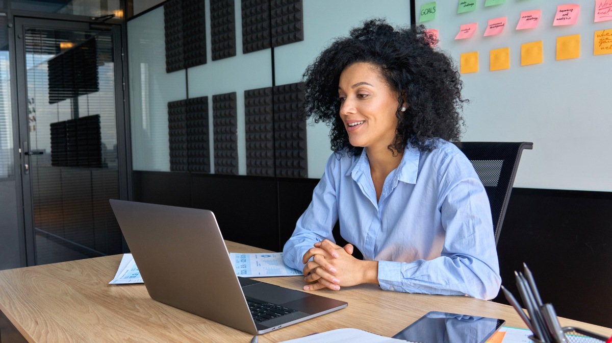 Professional woman sitting at a desk in front of laptop with her hands clasped