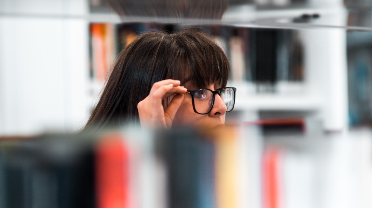 Woman in glasses looking over the top of a row of books