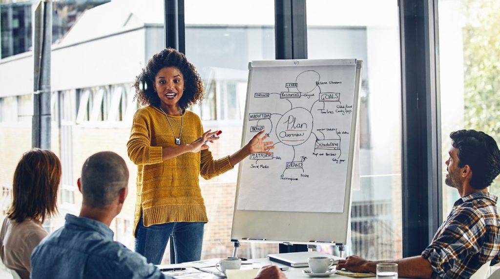 Professional woman standing in front of a giant notepad leading a meeting