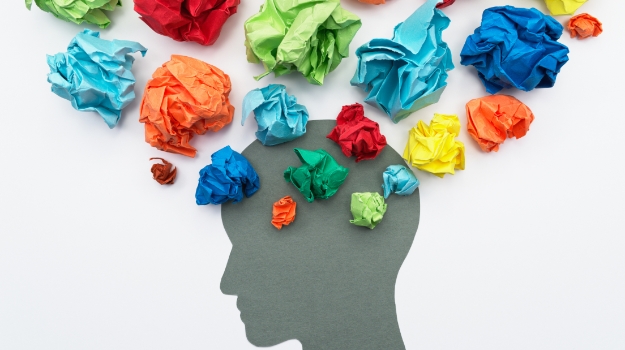 Illustration of a human head in silhouette with a cloud of colorful paper balls above it