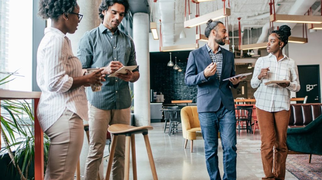 Two pairs of coworkers having separate discussions in an open-office workspace