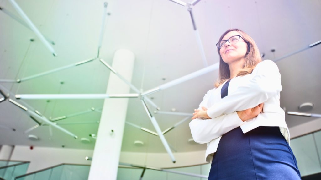Professional woman standing tall with arms crossed in an industrial office space