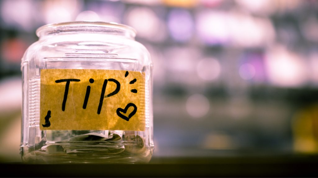 Tip jar on a counter with a cute hand-made label and folded bills inside