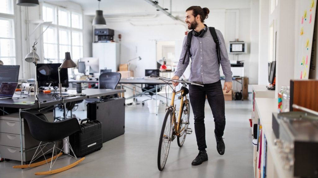 Man walking his bicycle into an open-plan office