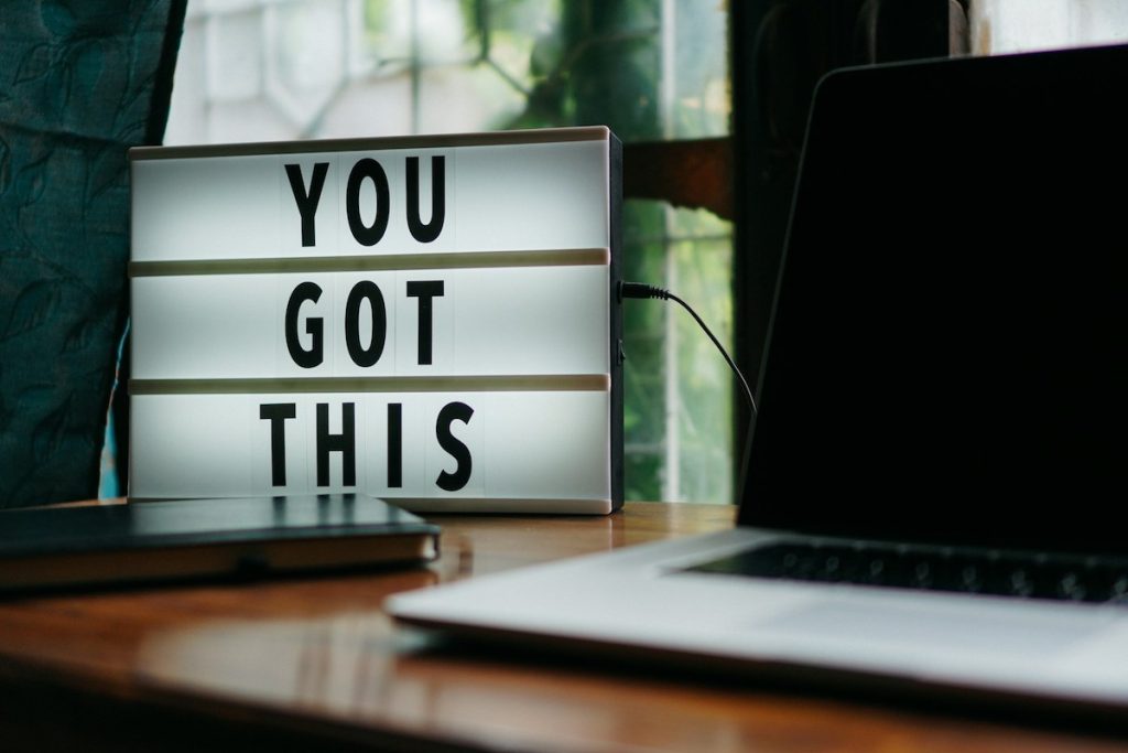 Light-up sign reading "You got this" next to a laptop on a desk
